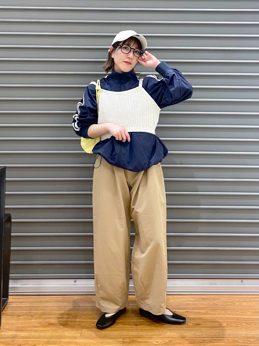 イエロー系のショルダーバッグ、ホワイト系のニット/セーター、ブラック系のパンプスを着用したレディースの春コーディネートの2枚目の写真
