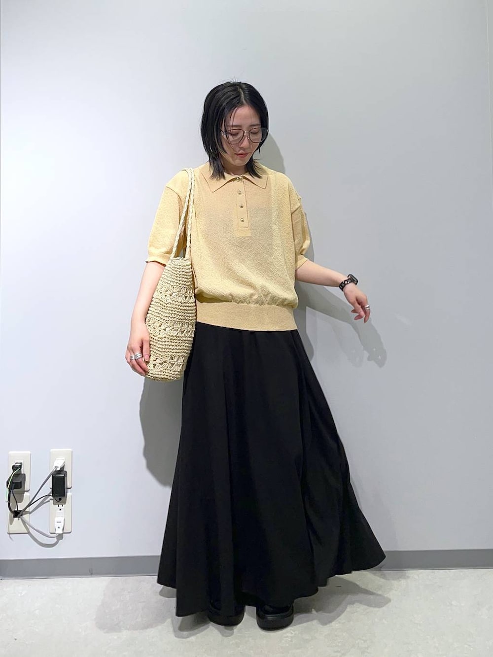 ブラック系のスカート、ブラック系のサンダル、ベージュ系のトートバッグを着用したレディースの春コーディネートの2枚目の写真