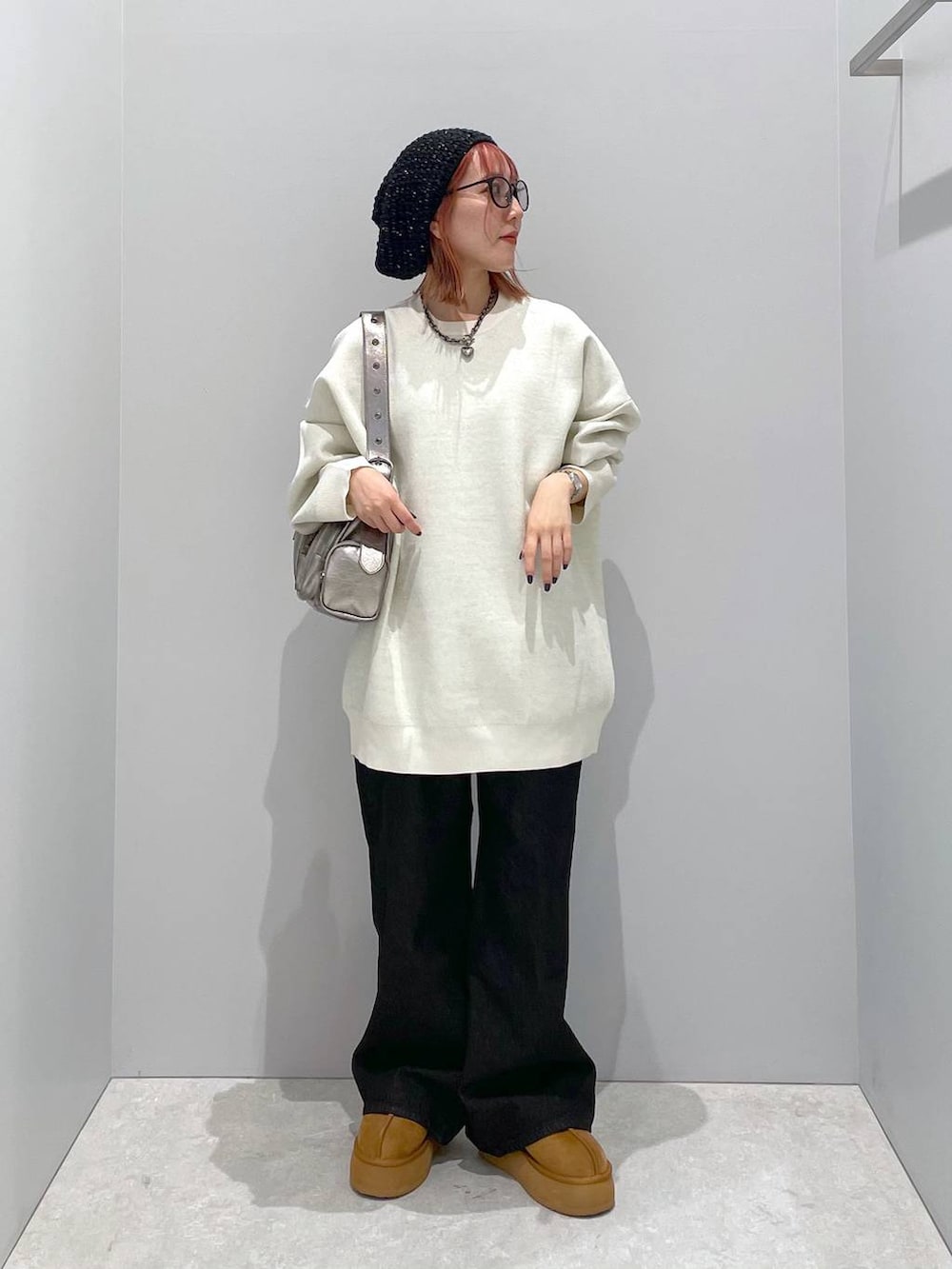 シルバー系のショルダーバッグ、ホワイト系のニット/セーター、ブラック系のデニムパンツを着用したレディースの秋コーディネートの3枚目の写真