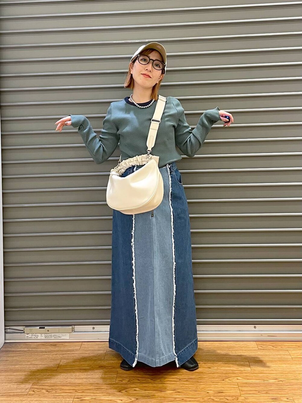 ホワイト系のショルダーバッグ、ブルー系のデニムスカート、グリーン系のTシャツ/カットソーを着用したレディースの春コーディネートの3枚目の写真
