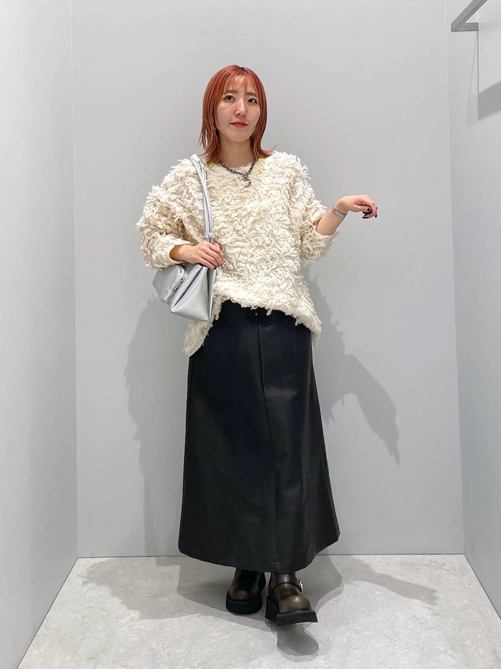 シルバー系のショルダーバッグ、グリーン系のブーツ、ホワイト系のニット/セーターを着用したレディースの秋コーディネートの2枚目の写真