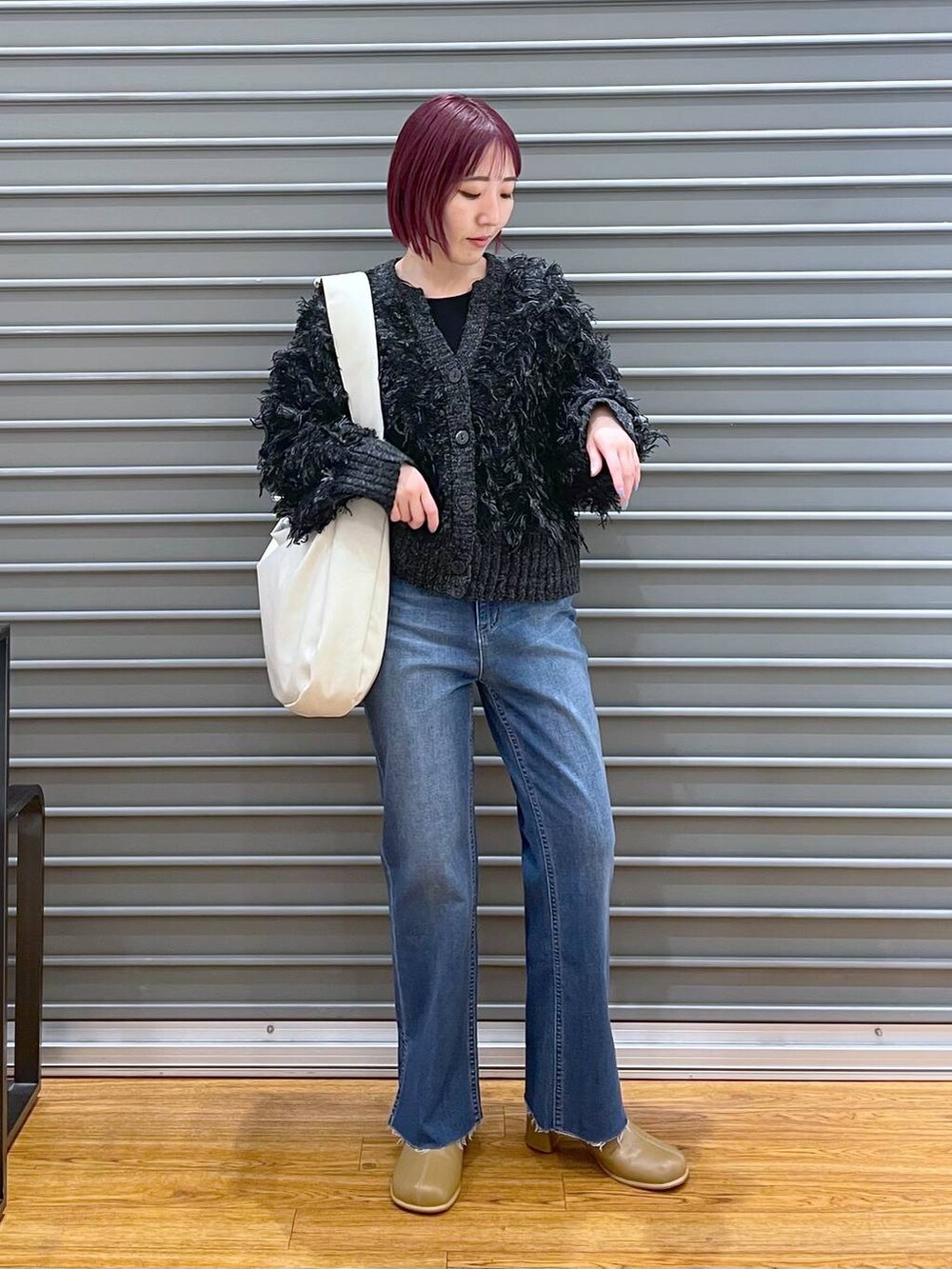 ブルー系のデニムパンツ、ホワイト系のショルダーバッグ、ブラウン系のブーツを着用したレディースの冬コーディネートの3枚目の写真