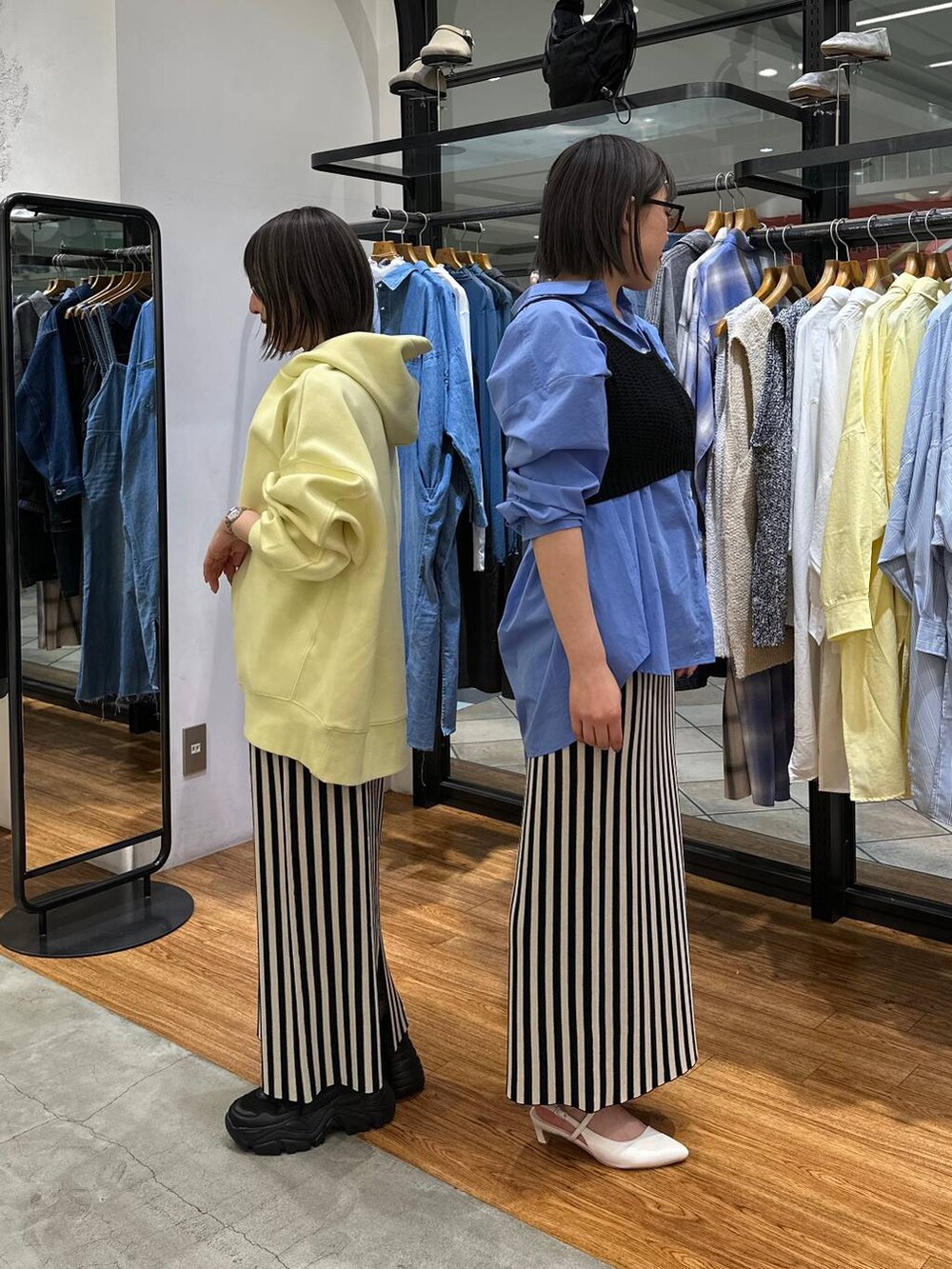 ブルー系のシャツ/ブラウス、ブラック系のニット/セーター、イエロー系のパーカーを着用したレディースの春コーディネートの2枚目の写真