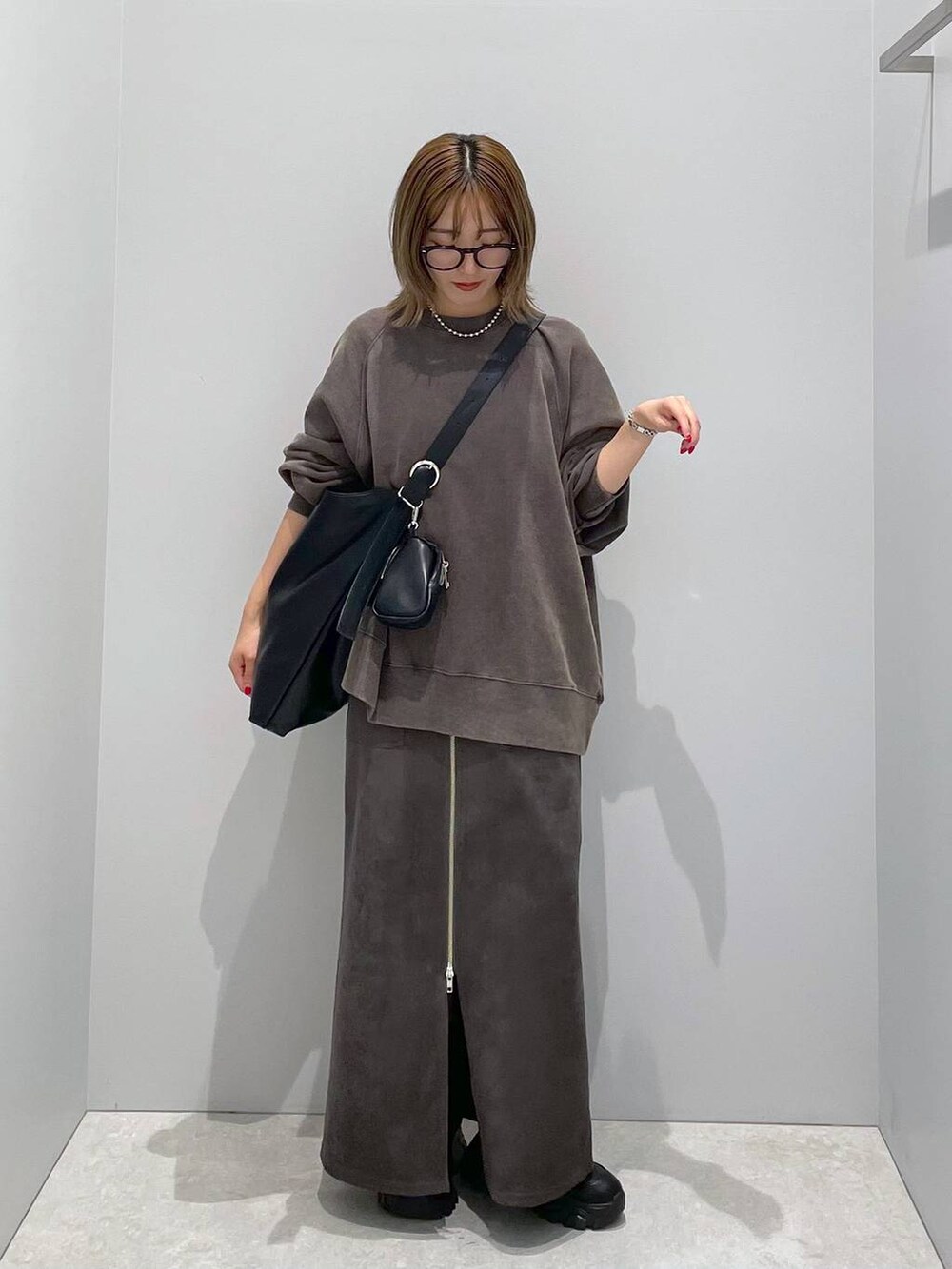 ブラック系のショルダーバッグ、ブラック系のスウェット、グレー系のスカートを着用したレディースの秋コーディネートの3枚目の写真