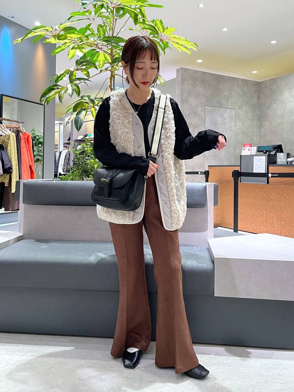 ブラック系のTシャツ/カットソー、ベージュ系のベスト、ブラック系のショルダーバッグを着用したレディースの秋コーディネートの3枚目の写真