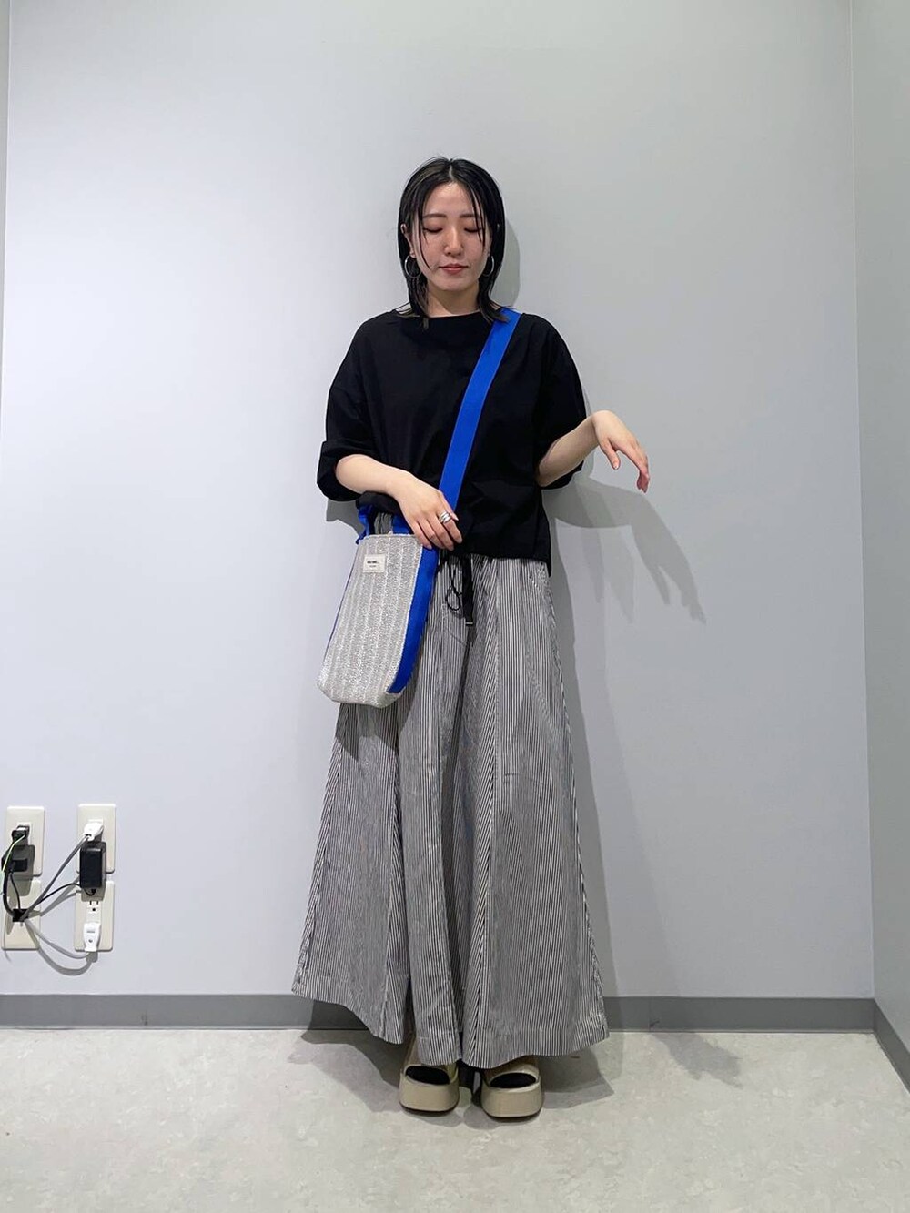 ブルー系のスカート、ホワイト系のサンダル、グレー系のトートバッグを着用したレディースの春コーディネートの2枚目の写真
