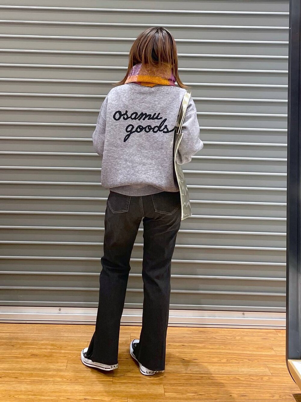 ブラック系のデニムパンツ、ゴールド系のトートバッグ、グレー系のニット/セーターを着用したレディースの秋コーディネートの3枚目の写真