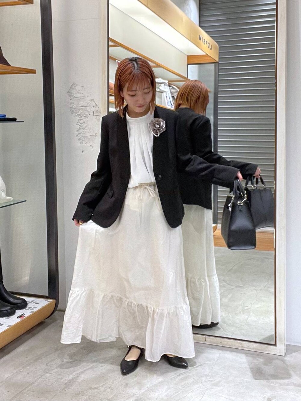 ホワイト系のスカート、ブラック系のノーカラージャケット、ホワイト系のシャツ/ブラウスを着用したレディースの冬コーディネートの3枚目の写真