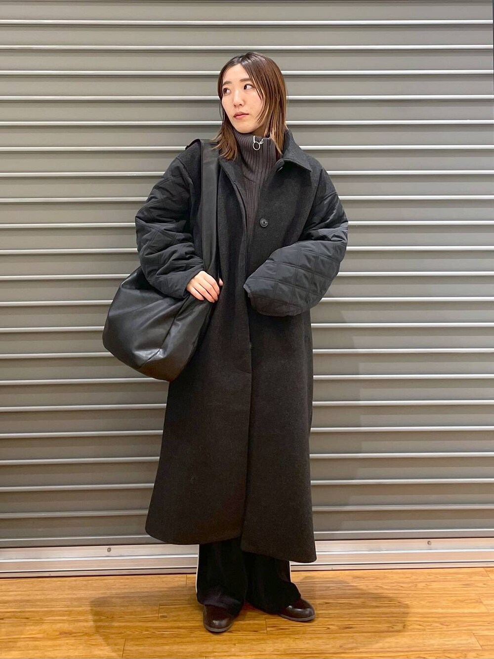 ブラック系のショルダーバッグ、ブラウン系のブーツ、グレー系のニット/セーターを着用したレディースの冬コーディネートの4枚目の写真