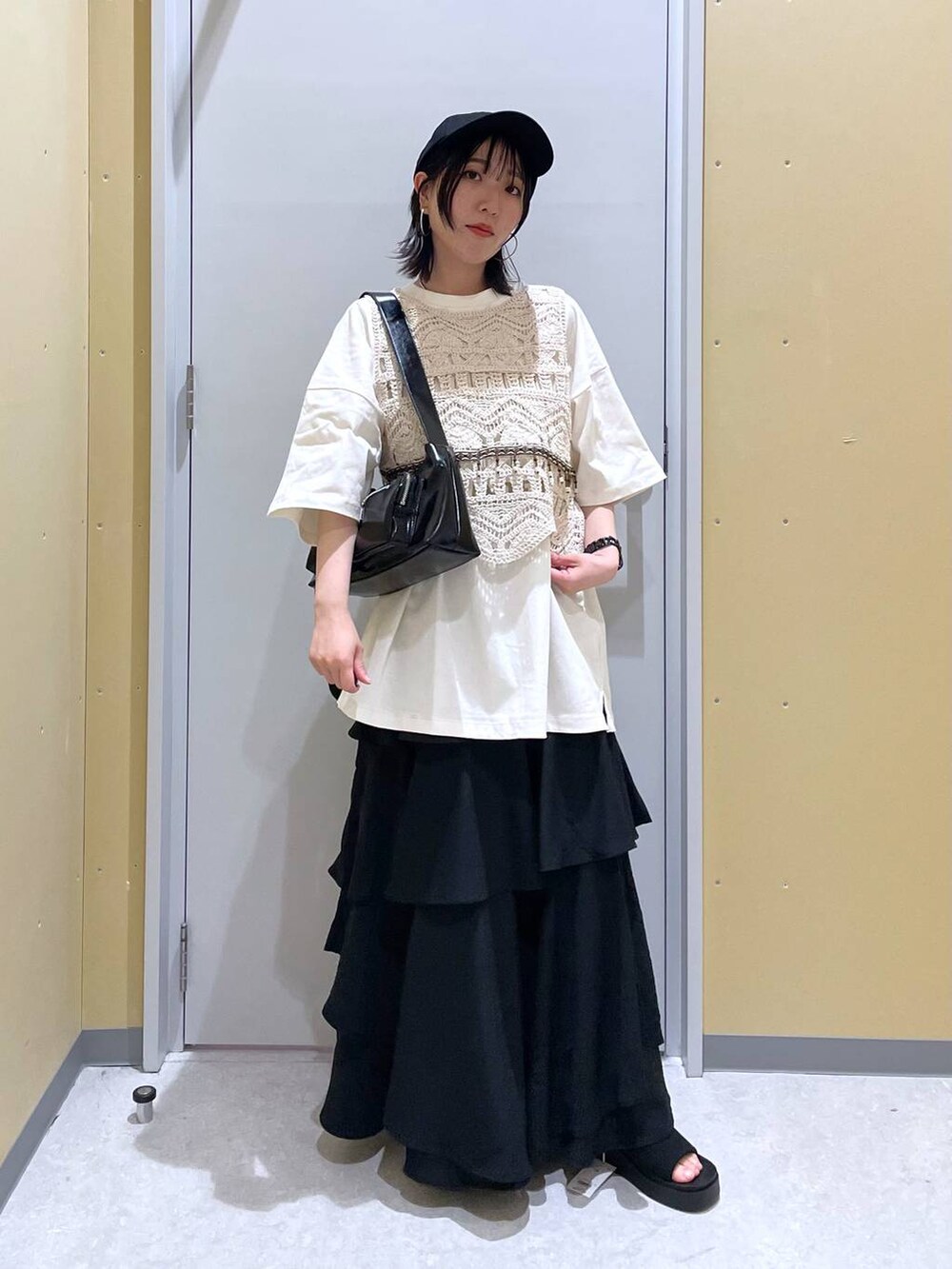 ブラック系のスカート、ブラック系のショルダーバッグ、ブラック系のサンダルを着用したレディースの春コーディネートの4枚目の写真