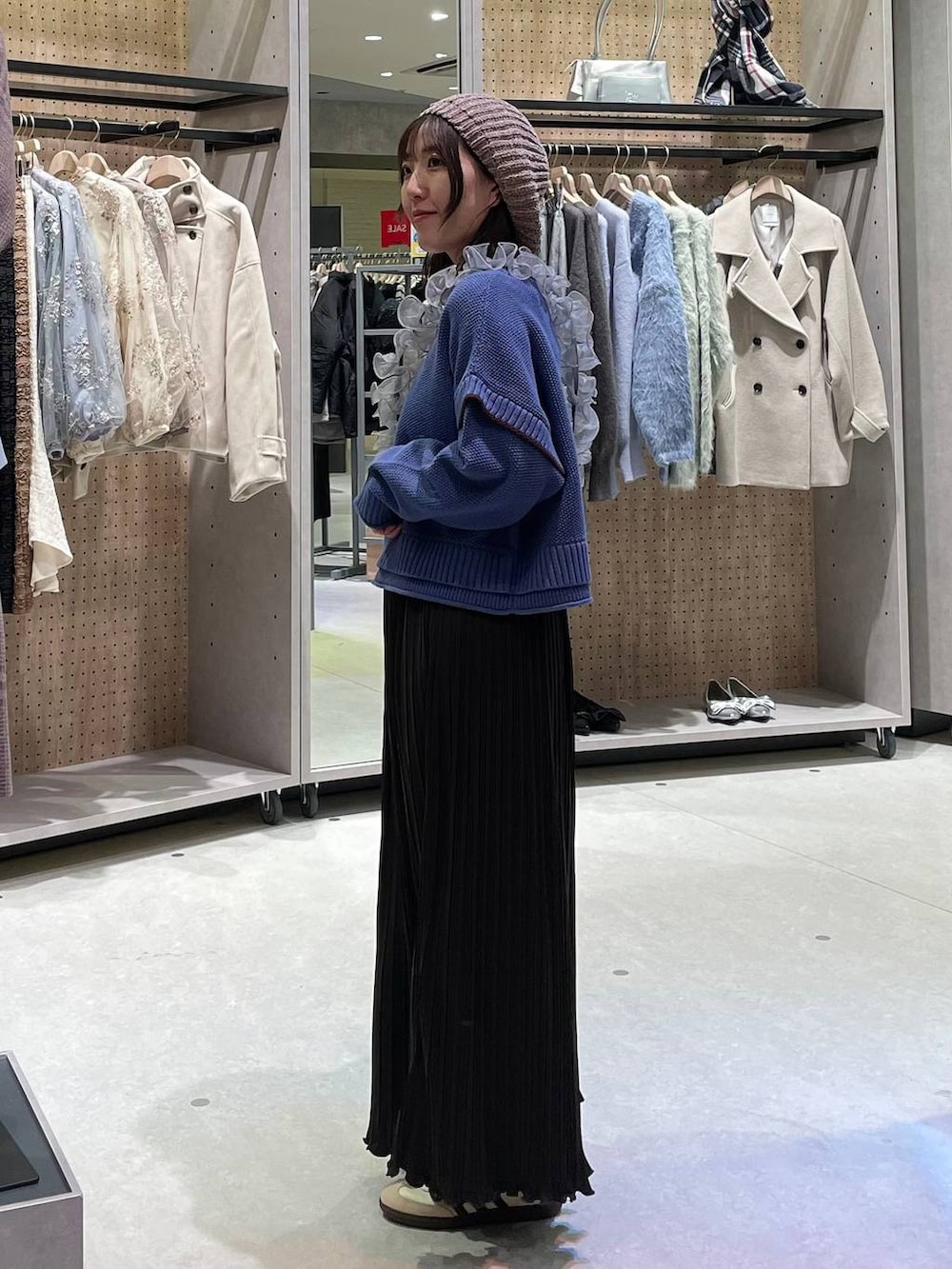 ベージュ系のワンピース、ブルー系のニット/セーター、グレー系のスマホグッズを着用したレディースの冬コーディネートの2枚目の写真