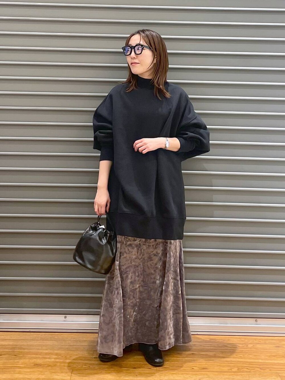 シルバー系のスカート、ブラック系のブーツ、ブラック系のチュニックを着用したレディースの冬コーディネートの3枚目の写真