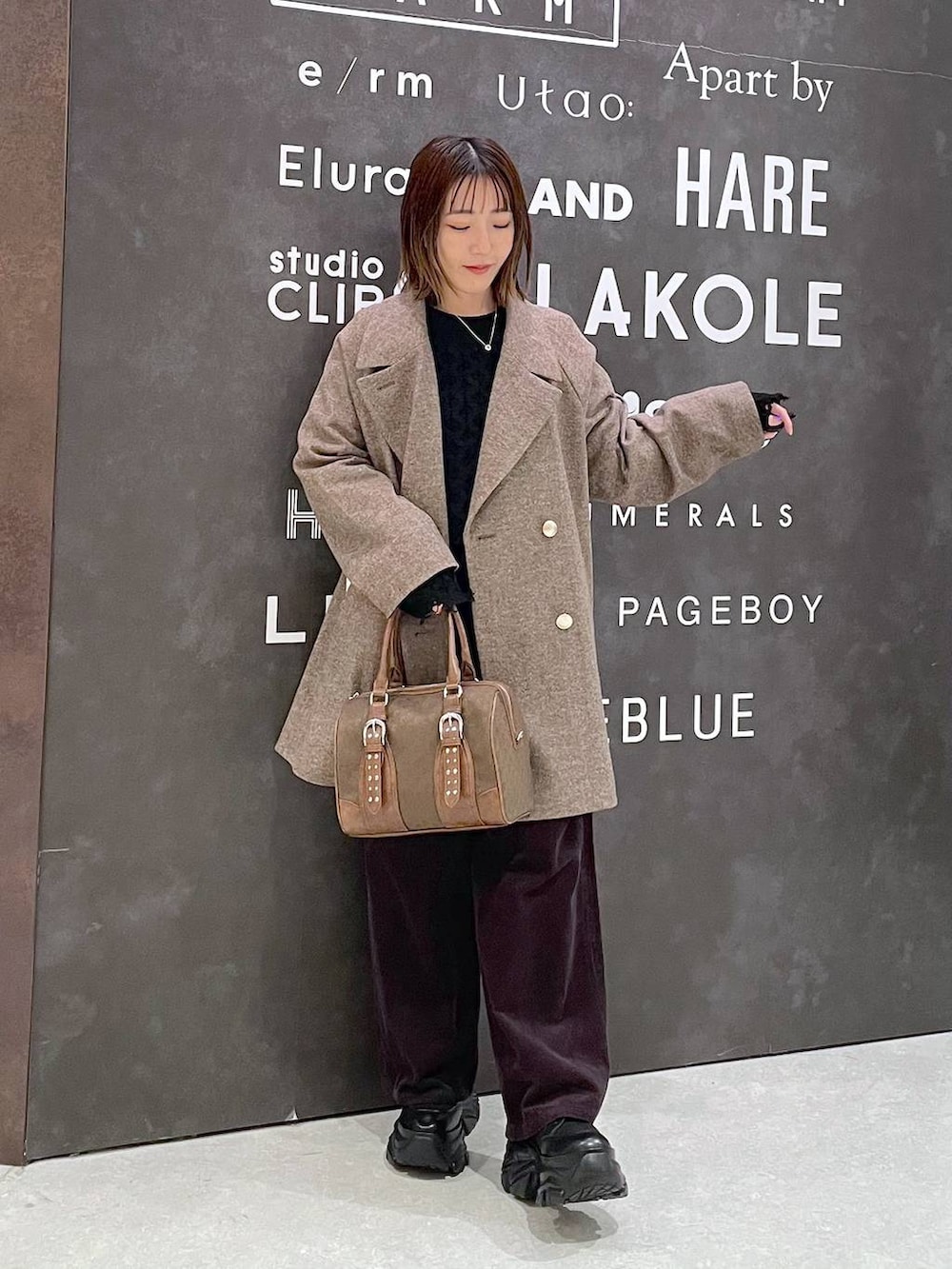 ブラック系のブーツ、ブラウン系のチェスターコート、ブラウン系のその他パンツを着用したレディースの秋コーディネートの3枚目の写真