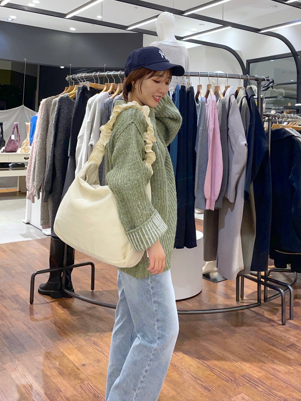 グリーン系のニット/セーター、ホワイト系のショルダーバッグ、ブルー系のデニムパンツを着用したレディースの秋コーディネートの4枚目の写真