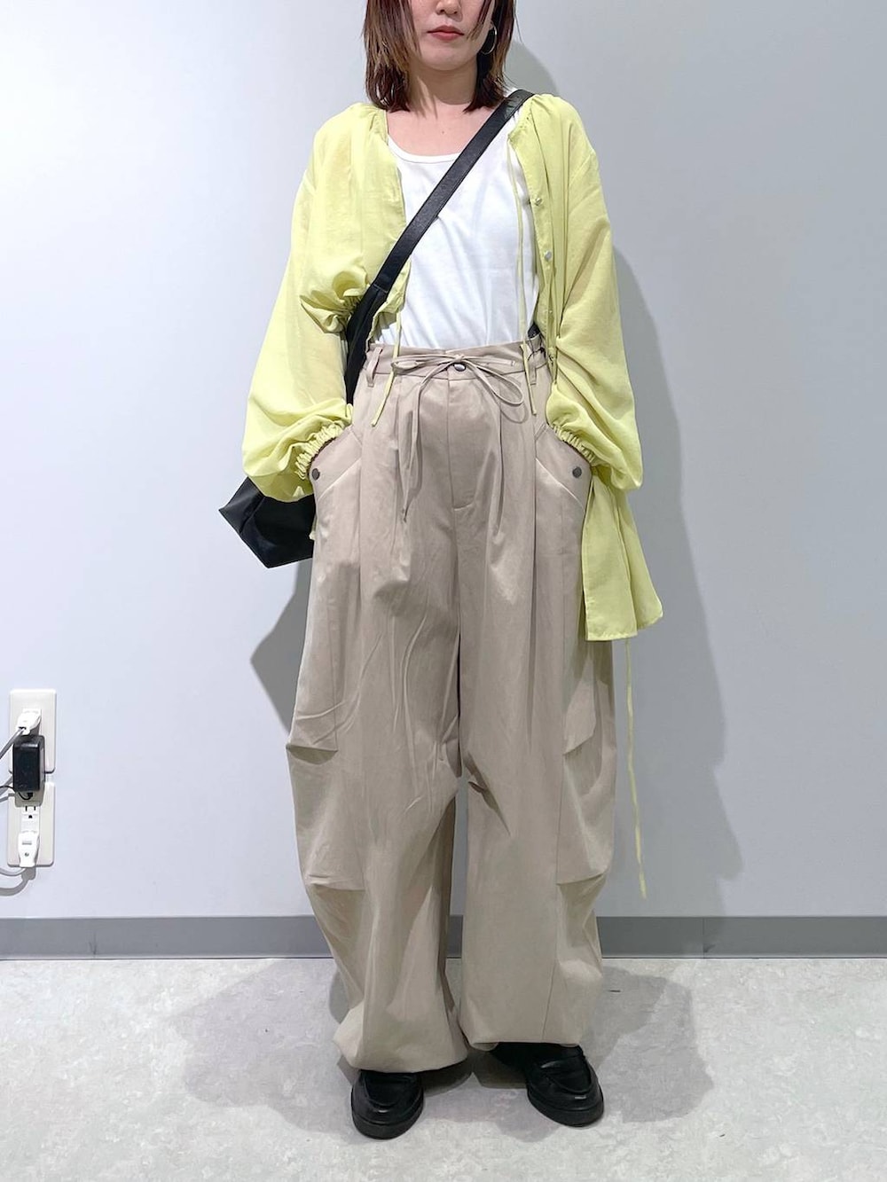 ブラック系のショルダーバッグ、イエロー系のシャツ/ブラウス、ベージュ系のその他パンツを着用したレディースの春コーディネートの2枚目の写真