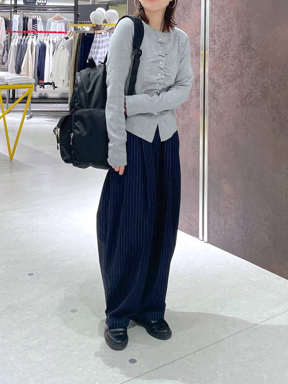 ブルー系のその他パンツ、ブラック系のバックパック/リュック、グレー系のカーディガン/ボレロを着用したレディースの春コーディネートの2枚目の写真