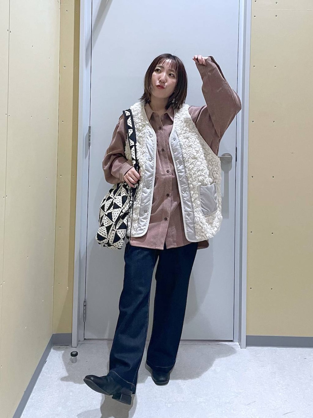 ベージュ系のベスト、ブルー系のデニムパンツ、ピンク系のシャツ/ブラウスを着用したレディースの秋コーディネートの3枚目の写真