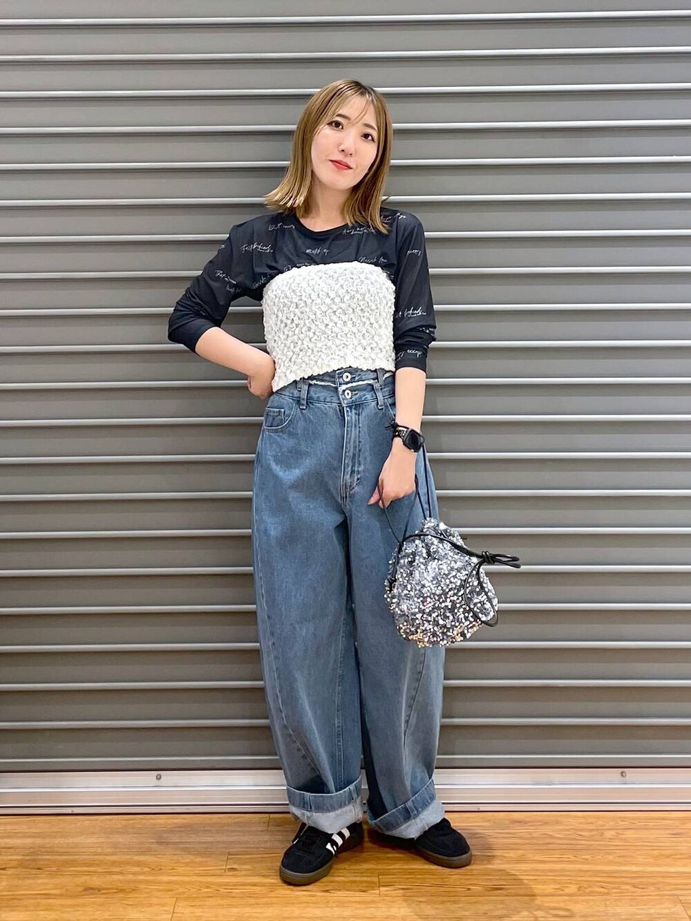 ブルー系のデニムパンツ、ブラック系のスニーカー、シルバー系のショルダーバッグを着用したレディースの秋コーディネートの2枚目の写真