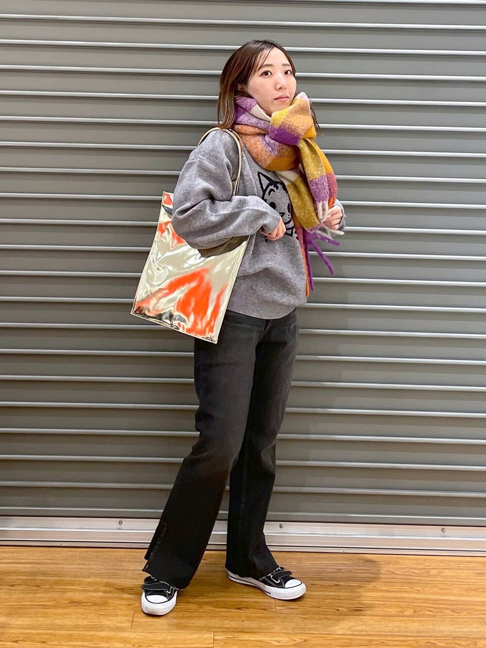 ブラック系のデニムパンツ、ゴールド系のトートバッグ、グレー系のニット/セーターを着用したレディースの秋コーディネートの2枚目の写真