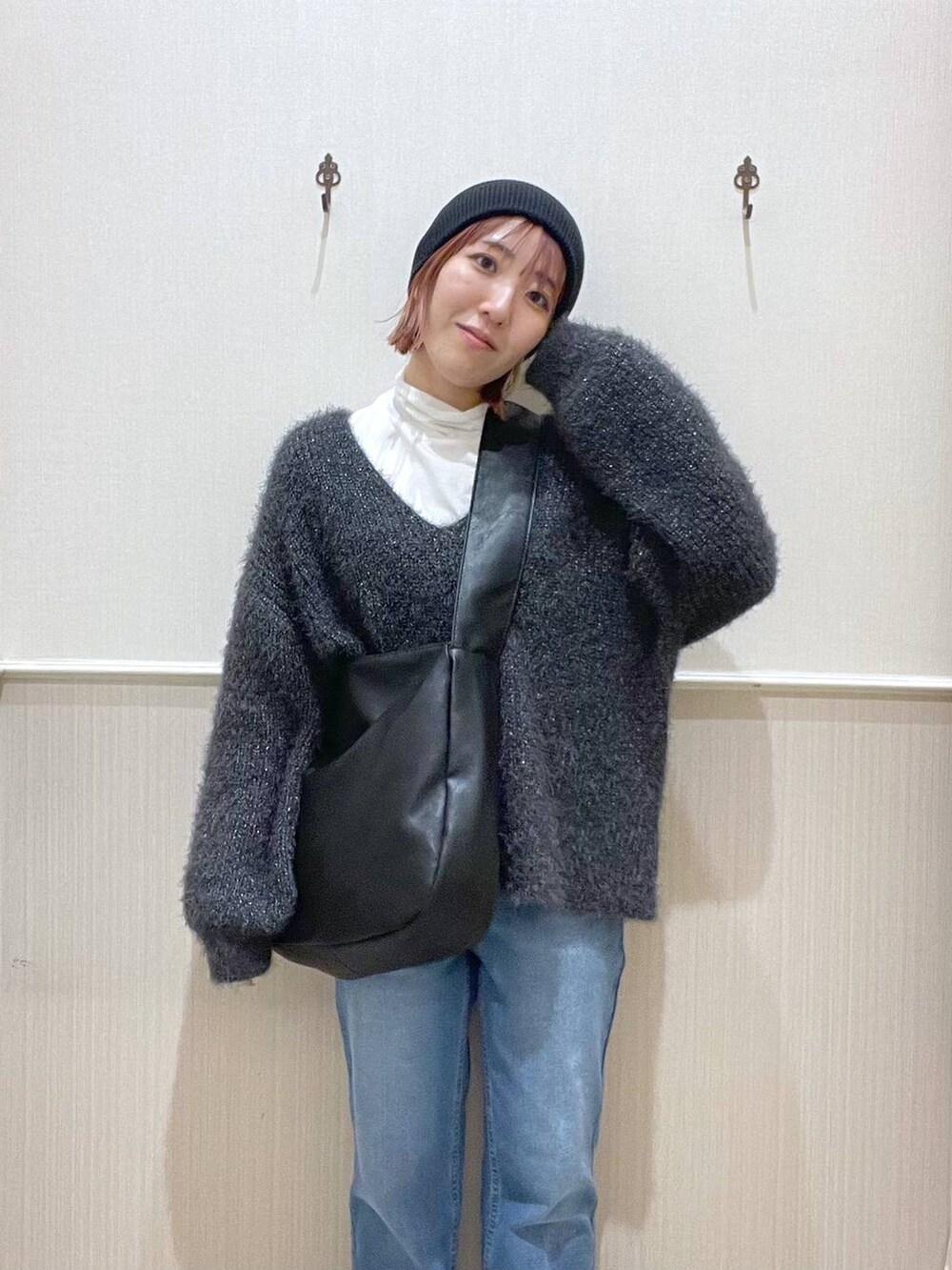 ブラック系のショルダーバッグ、ホワイト系のTシャツ/カットソー、グレー系のニット/セーターを着用したレディースの冬コーディネートの2枚目の写真