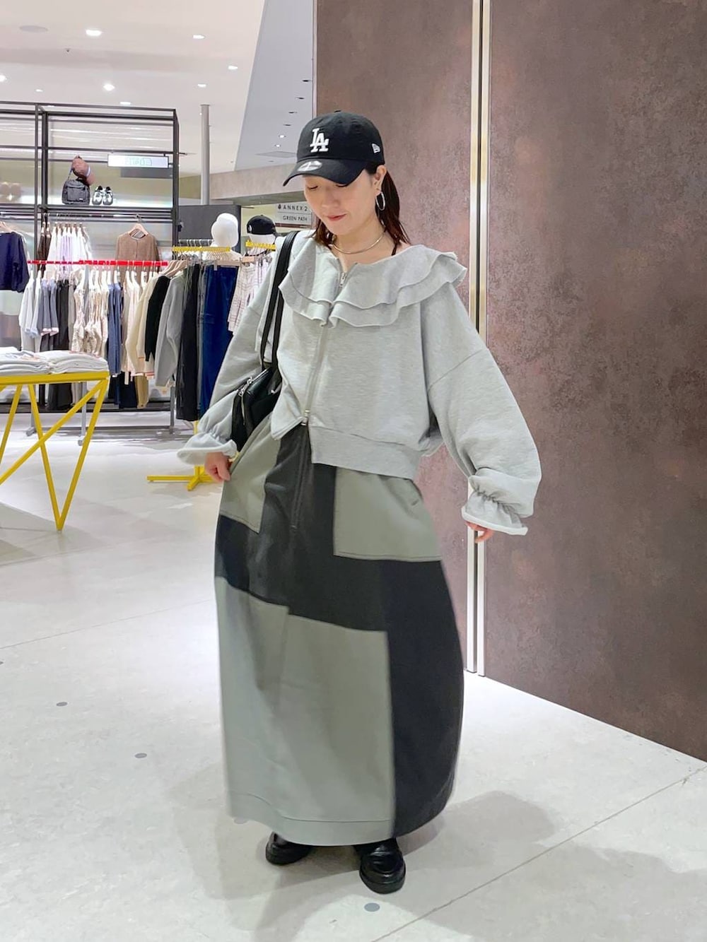 ブラック系のショルダーバッグ、グリーン系のスカートを着用したレディースの春コーディネートの3枚目の写真