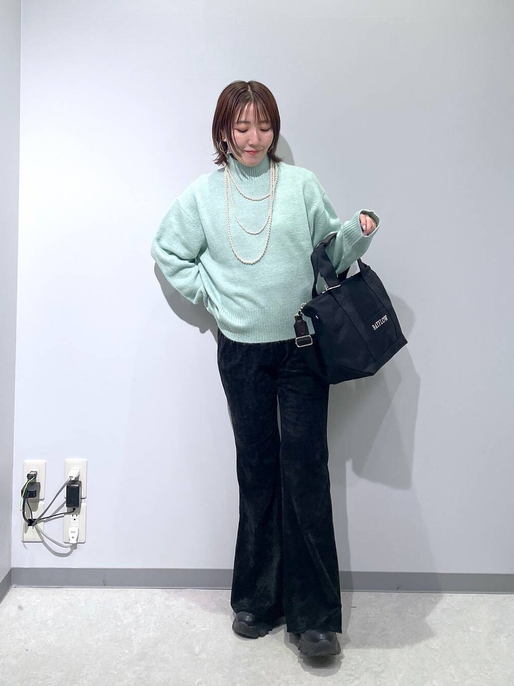 グリーン系のニット/セーター、ブラック系のその他パンツ、ブラック系のトートバッグを着用したレディースの冬コーディネートの3枚目の写真