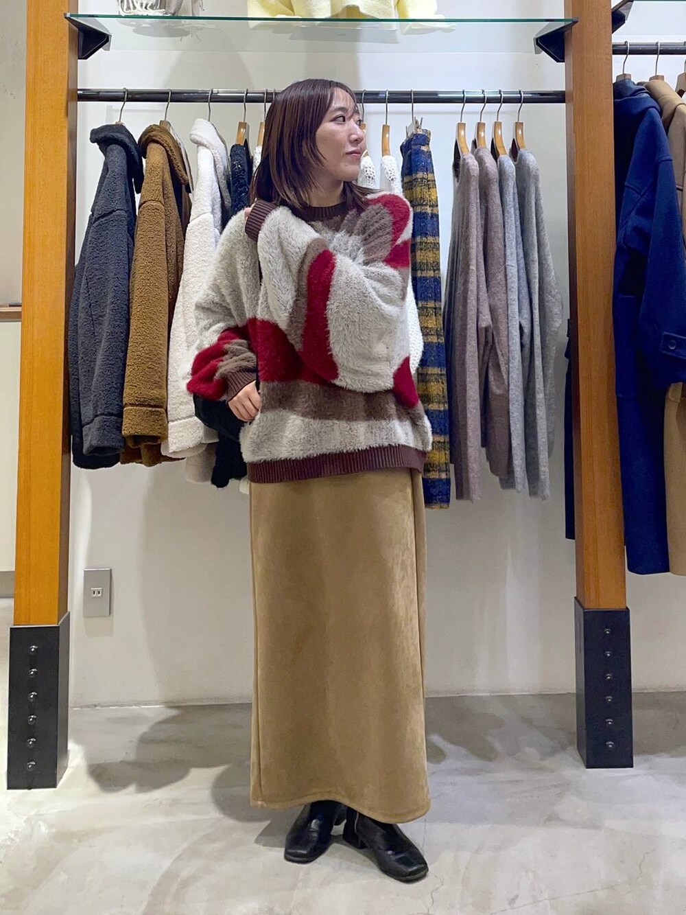 ブラック系のショルダーバッグ、ベージュ系のスカート、ブラウン系のニット/セーターを着用したレディースの冬コーディネートの2枚目の写真