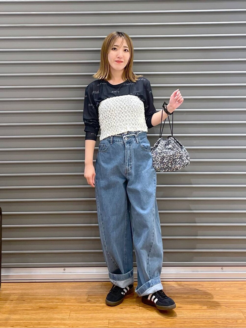 ブルー系のデニムパンツ、ブラック系のスニーカー、シルバー系のショルダーバッグを着用したレディースの秋コーディネートの3枚目の写真