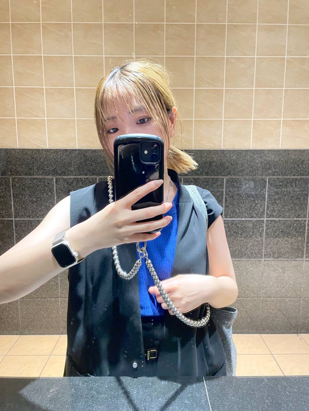 ブラック系のスラックス、シルバー系のスマホグッズを着用したレディースの夏コーディネートの3枚目の写真