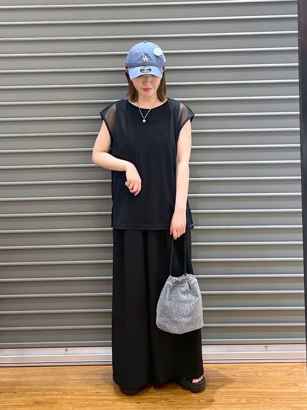 ブラック系のスラックス、グレー系のショルダーバッグ、ブラック系のTシャツ/カットソーを着用したレディースの夏コーディネートの2枚目の写真