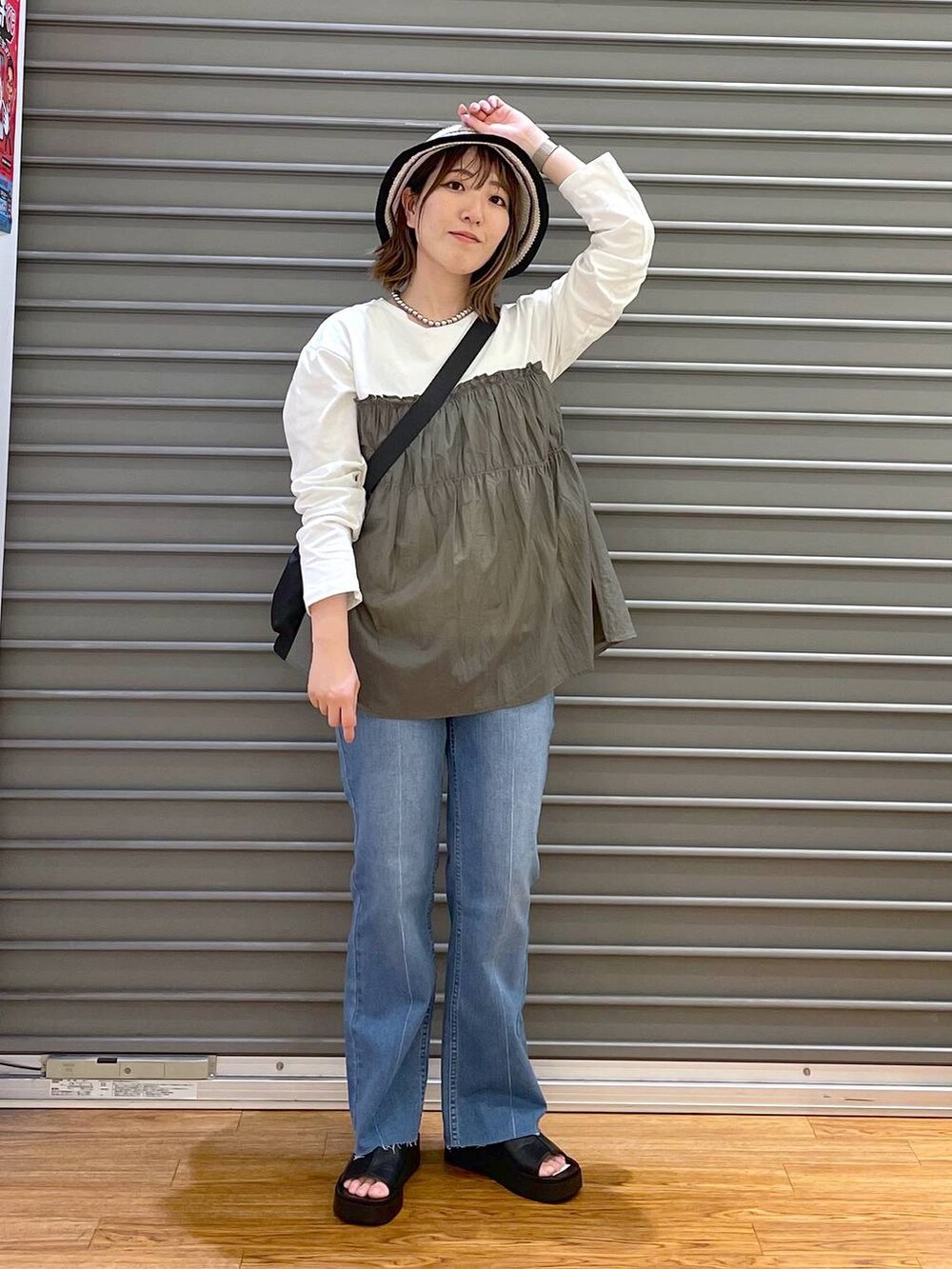 グリーン系のTシャツ/カットソー、ブラック系のショルダーバッグ、ブルー系のデニムパンツを着用したレディースの春コーディネートの2枚目の写真