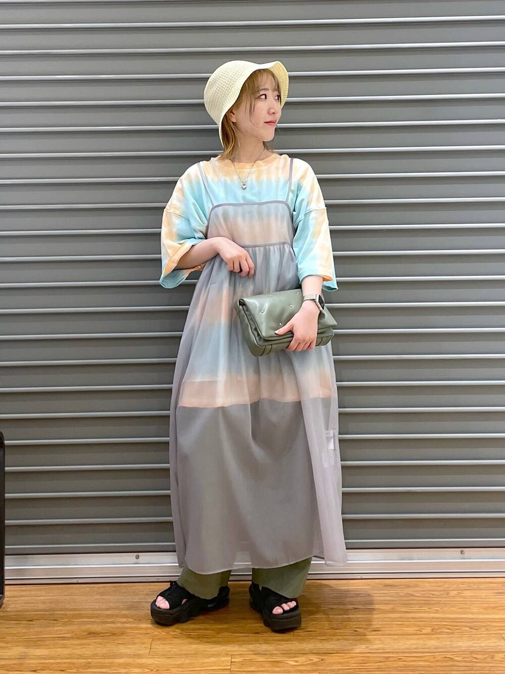 グリーン系のその他パンツ、グリーン系のショルダーバッグ、オレンジ系のTシャツ/カットソーを着用したレディースの春コーディネートの2枚目の写真