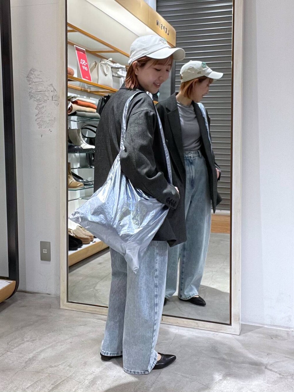 ブルー系のデニムパンツ、ブラック系のテーラードジャケット、シルバー系のトートバッグを着用したレディースの春コーディネートの4枚目の写真