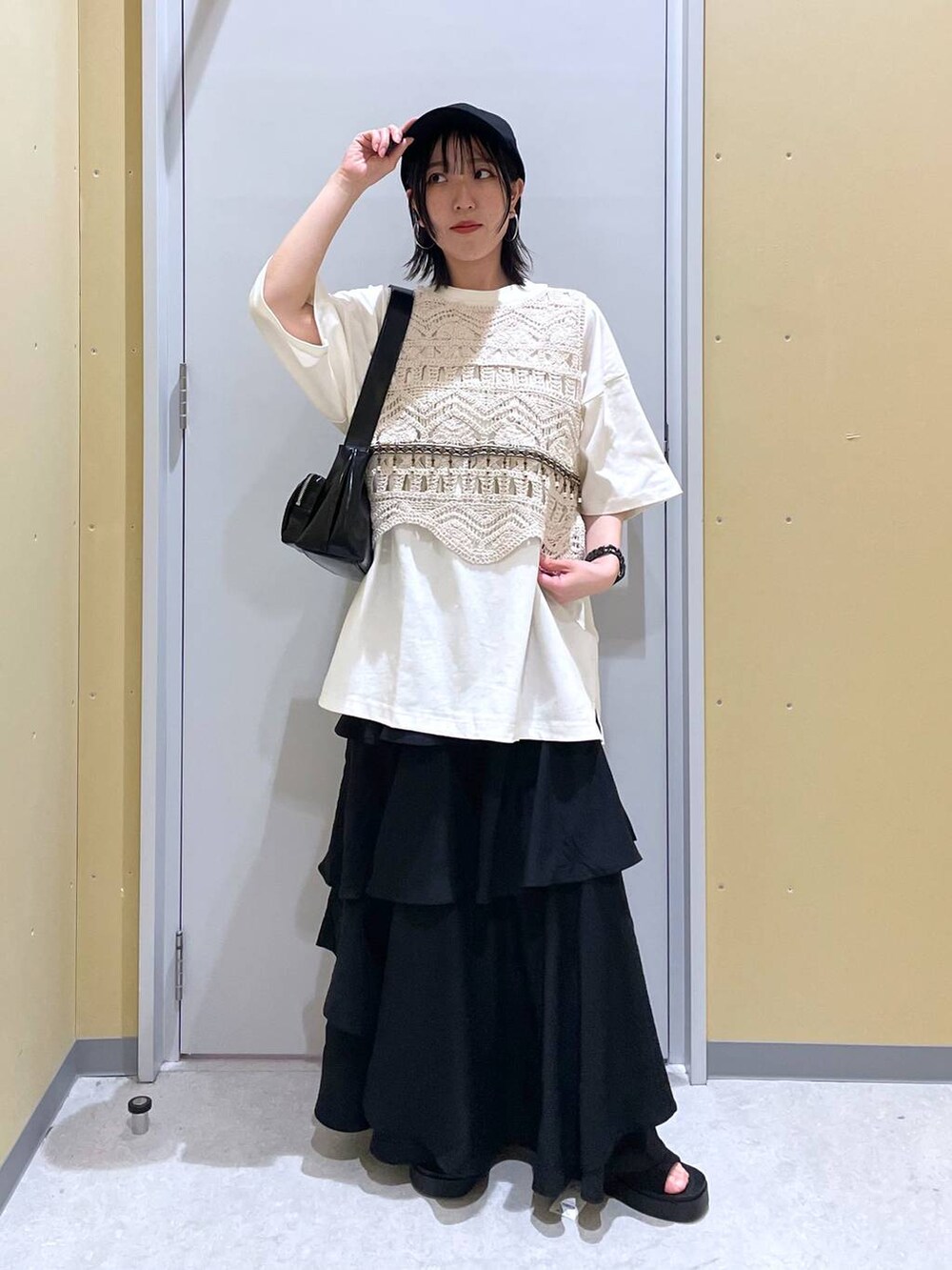 ブラック系のスカート、ブラック系のショルダーバッグ、ブラック系のサンダルを着用したレディースの春コーディネートの2枚目の写真