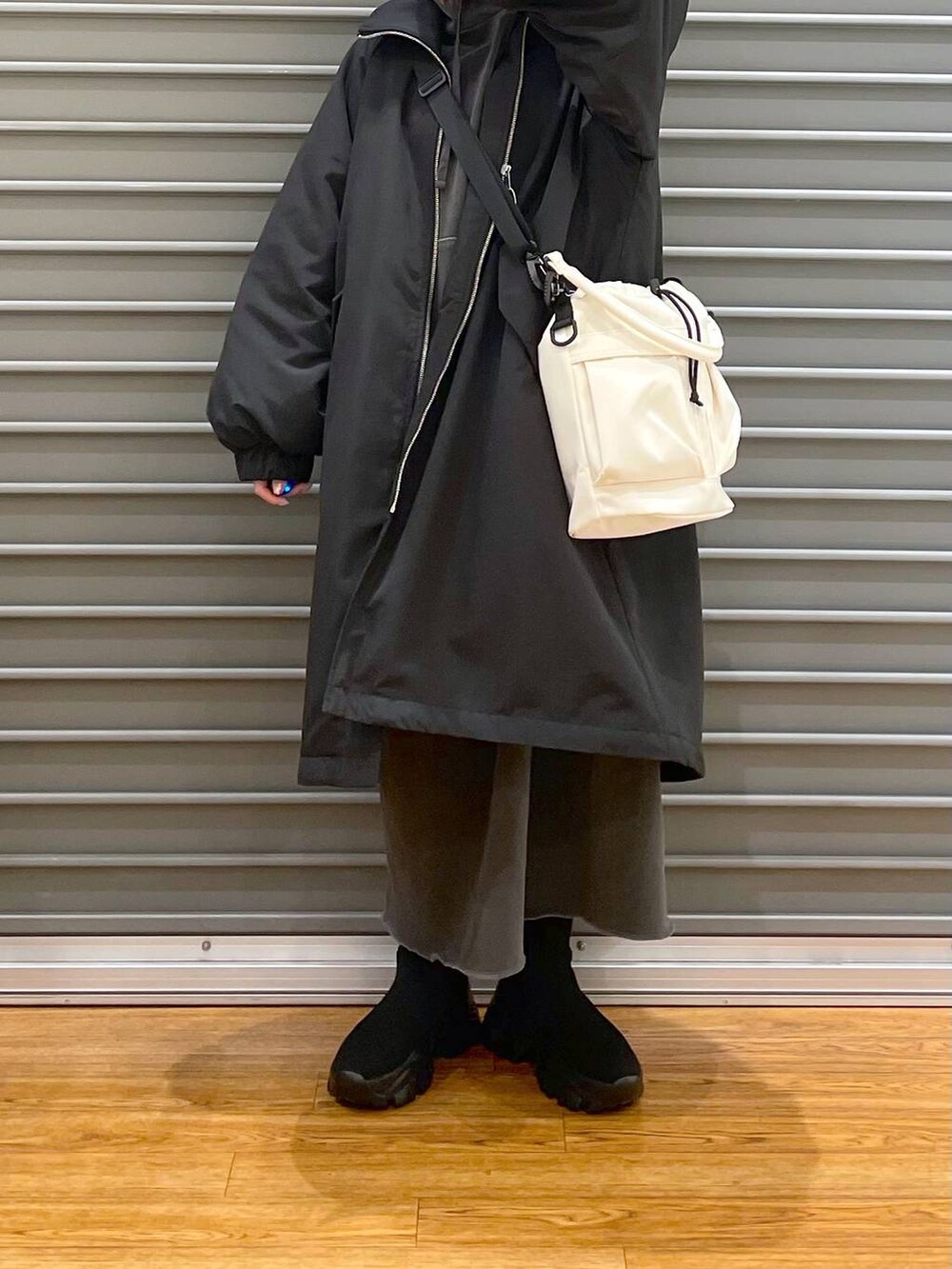 ブラック系のその他アウター、ブラック系のブーツ、ホワイト系のショルダーバッグを着用したレディースの冬コーディネートの4枚目の写真