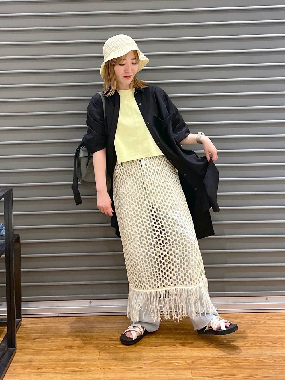 グリーン系のショルダーバッグ、ブルー系のデニムパンツ、ブラック系のチュニックを着用したレディースの夏コーディネートの2枚目の写真