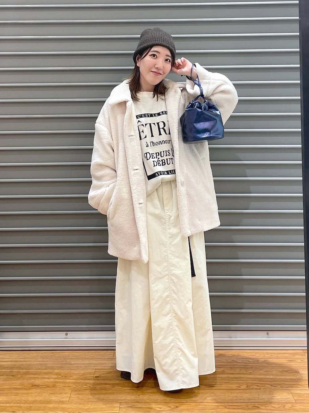 ホワイト系のブルゾン、ホワイト系のニット/セーター、ブルー系のショルダーバッグを着用したレディースの冬コーディネートの2枚目の写真