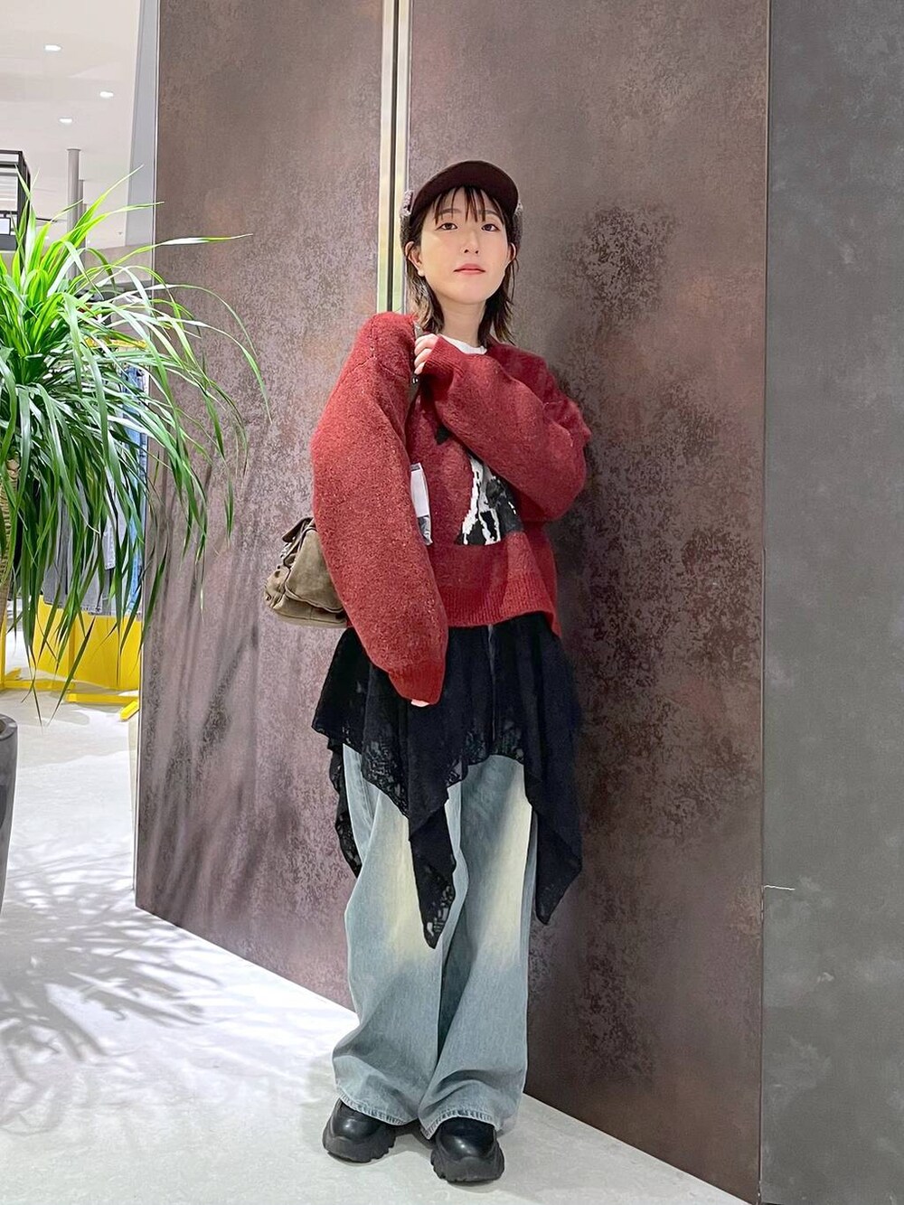 ブルー系のデニムパンツ、ブラウン系のショルダーバッグ、レッド系のニット/セーターを着用したレディースの秋コーディネートの4枚目の写真