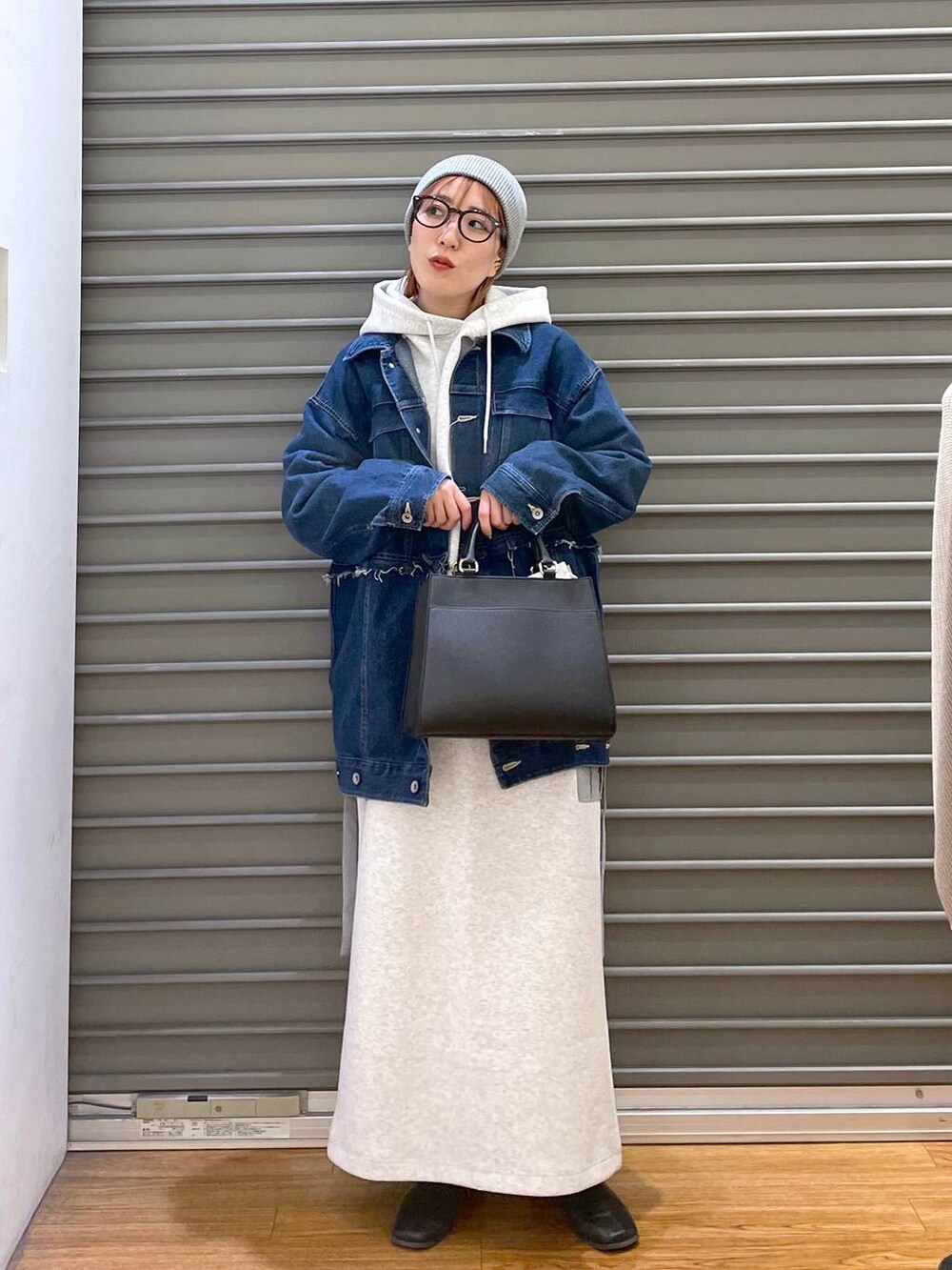 ブルー系のデニムジャケット、グレー系のスカート、ブラック系のショルダーバッグを着用したレディースの冬コーディネートの3枚目の写真