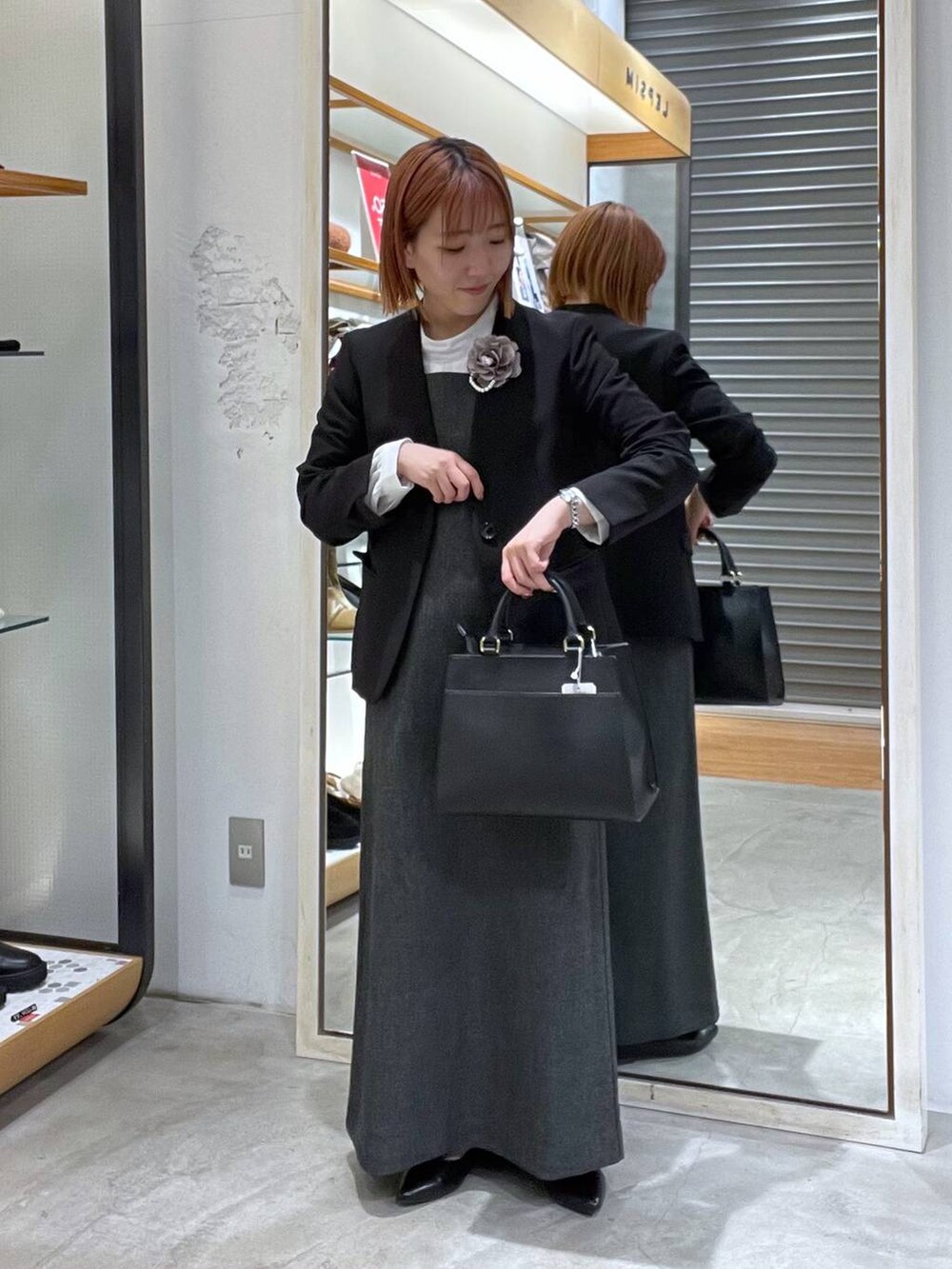 ブラック系のノーカラージャケット、ホワイト系のシャツ/ブラウス、ブラック系のショルダーバッグを着用したレディースの冬コーディネートの3枚目の写真