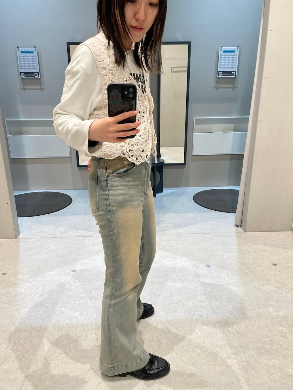 ブルー系のデニムパンツ、ベージュ系のベストを着用したレディースの春コーディネートの3枚目の写真