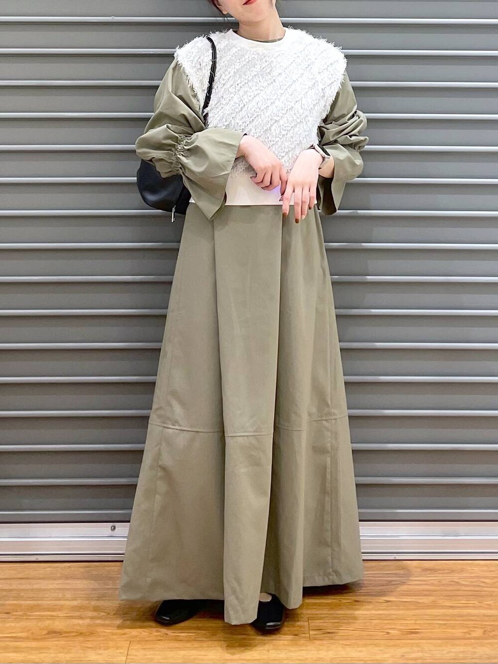 ホワイト系のベスト、ブラック系のパンプス、グリーン系のワンピースを着用したレディースの春コーディネートの3枚目の写真