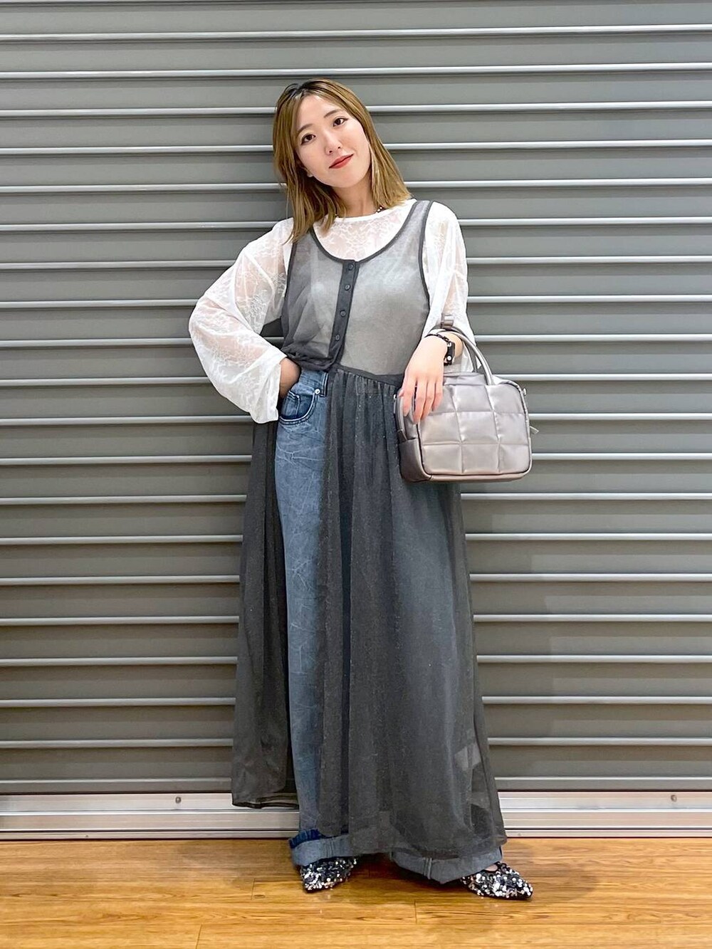 シルバー系のパンプス、グレー系のワンピース、ブルー系のデニムパンツを着用したレディースの秋コーディネートの2枚目の写真