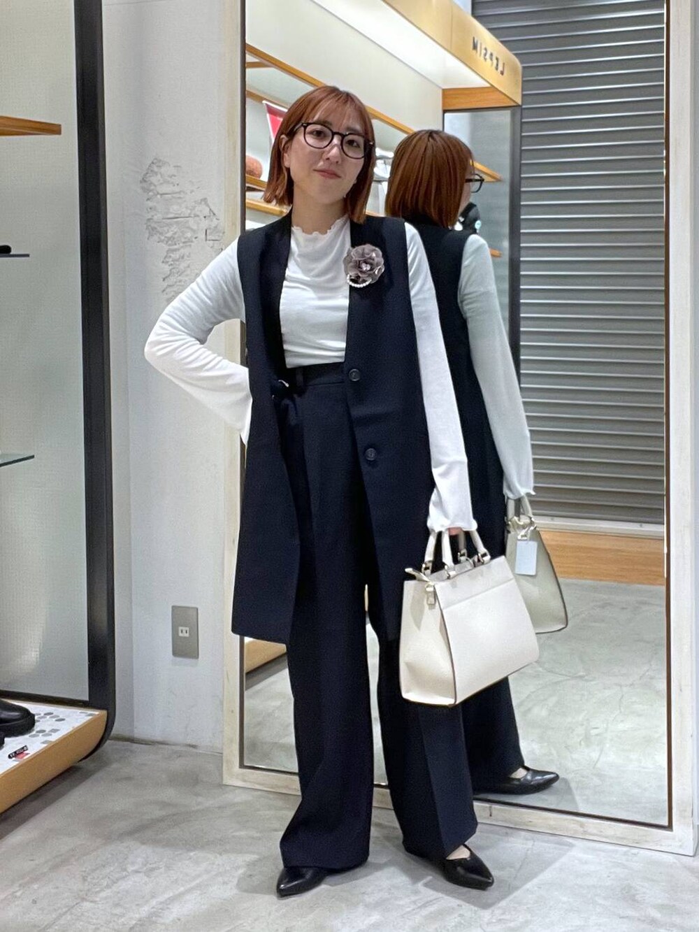 ホワイト系のTシャツ/カットソー、ホワイト系のショルダーバッグ、ブラック系のパンプスを着用したレディースの冬コーディネートの2枚目の写真