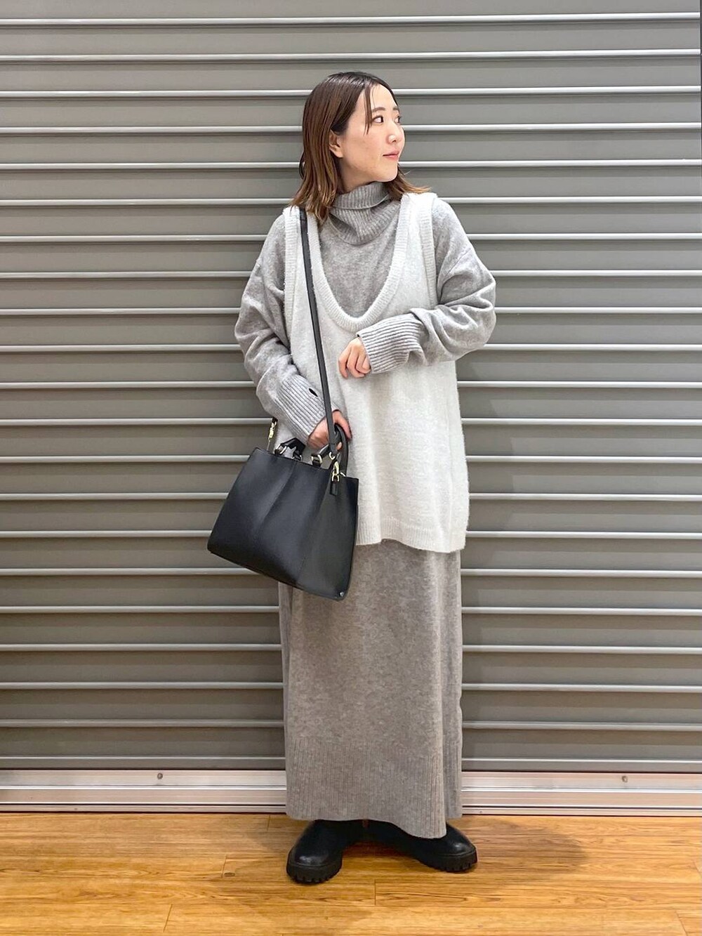 ブラック系のブーツ、グレー系のワンピース、ブラック系のショルダーバッグを着用したレディースの冬コーディネートの2枚目の写真