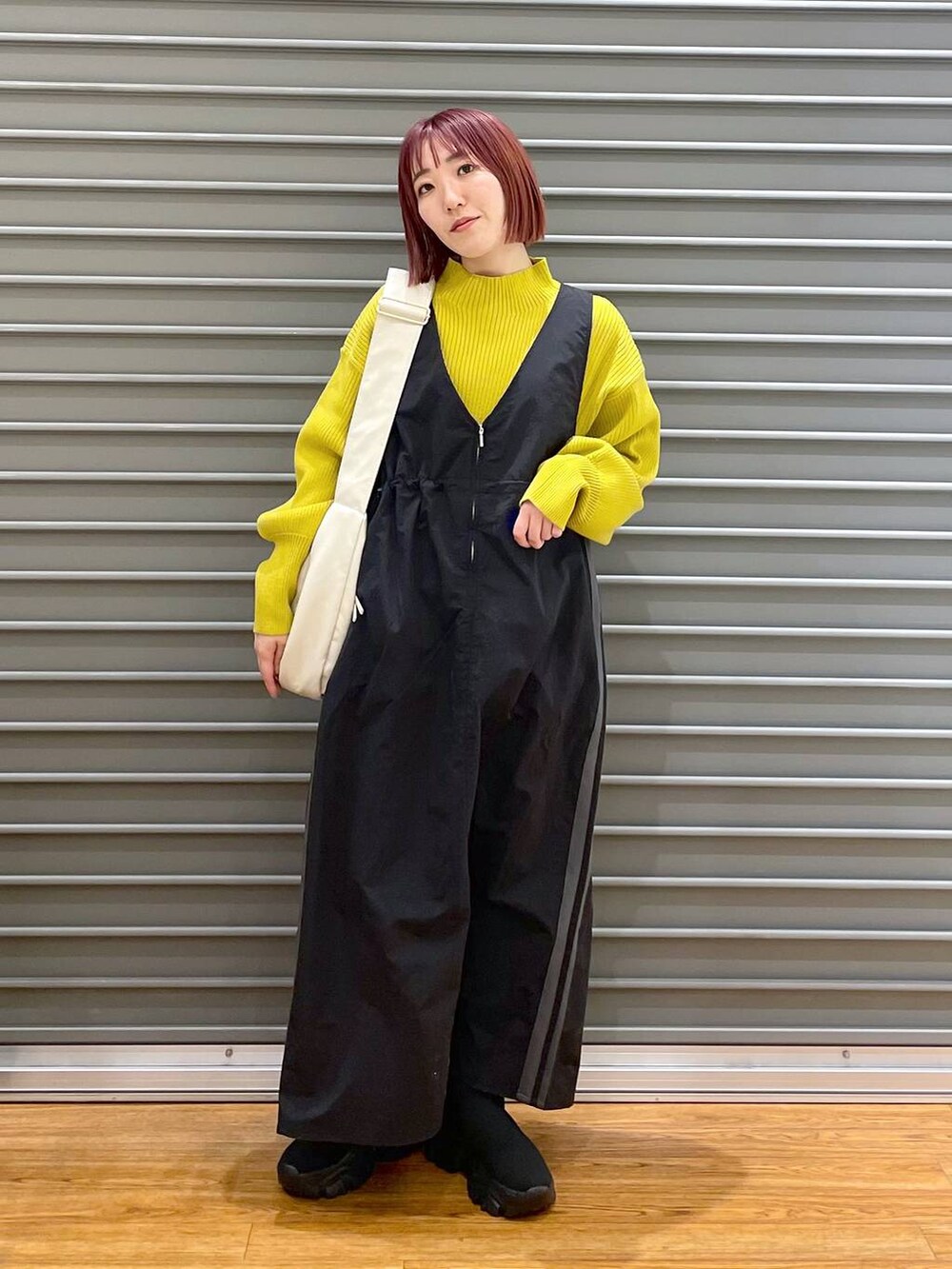 イエロー系のニット/セーター、ホワイト系のショルダーバッグ、ブラック系のブーツを着用したレディースの冬コーディネートの2枚目の写真