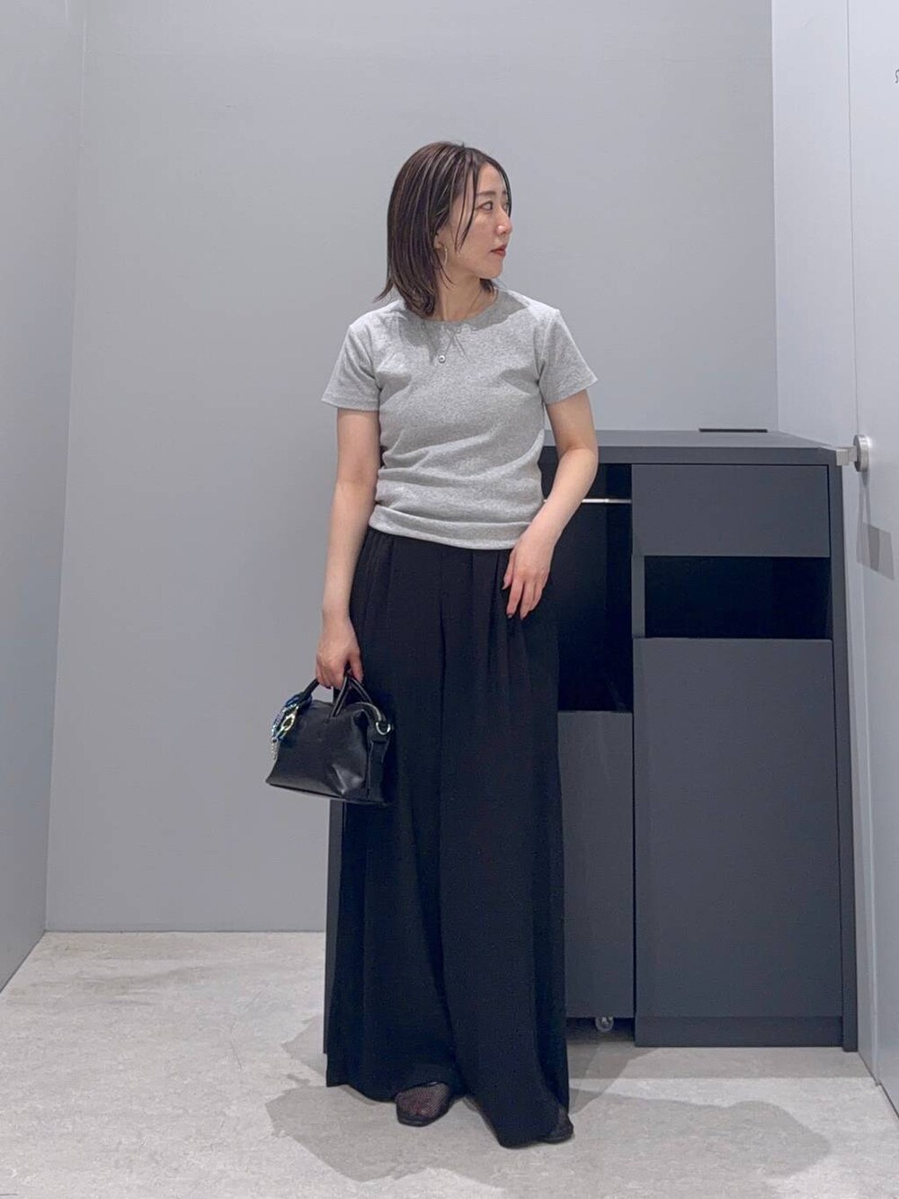 ブラック系のその他パンツ、ブラック系のボストンバッグ、グレー系のTシャツ/カットソーを着用したレディースの夏コーディネートの2枚目の写真