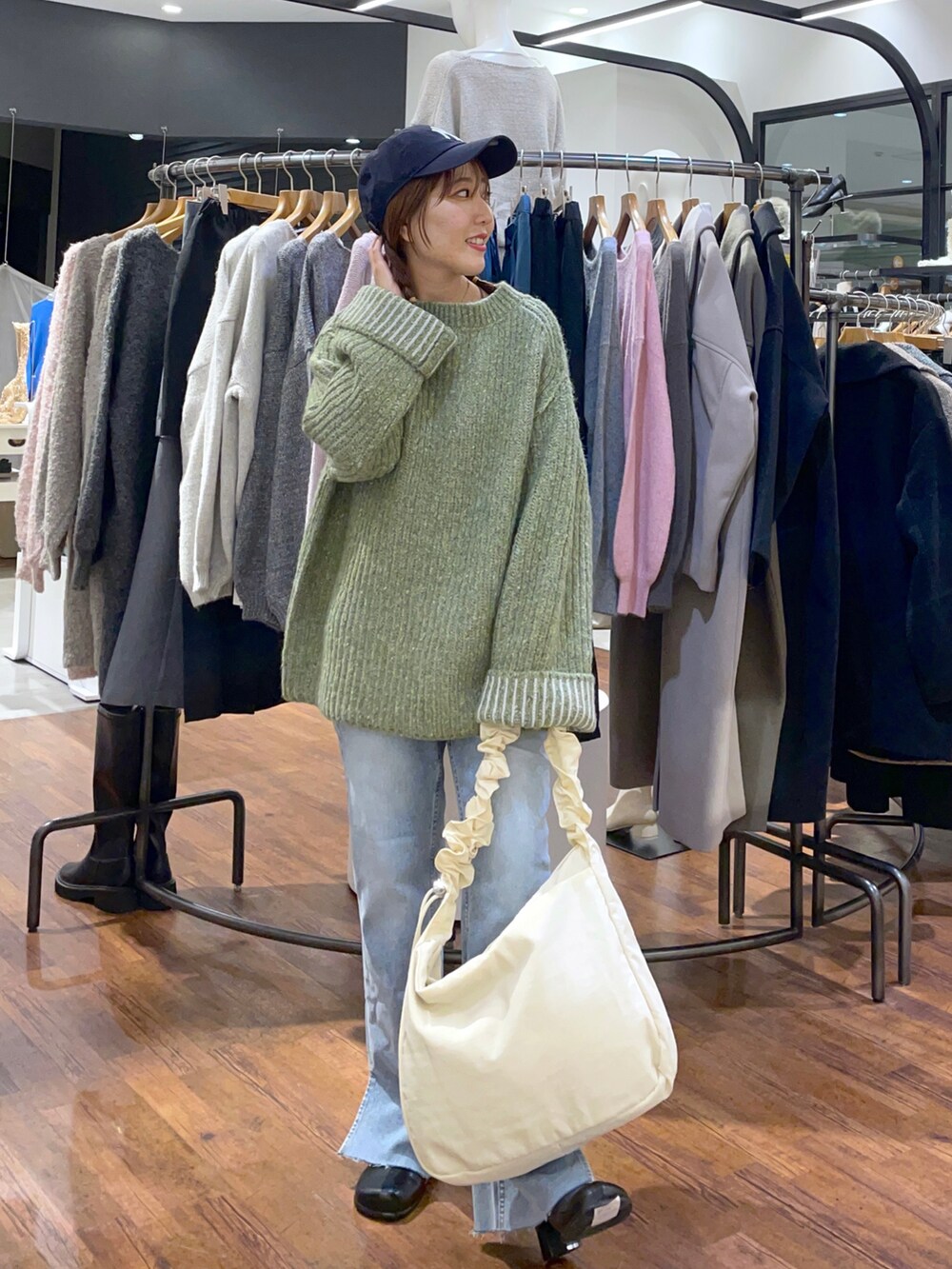 グリーン系のニット/セーター、ホワイト系のショルダーバッグ、ブルー系のデニムパンツを着用したレディースの秋コーディネートの5枚目の写真