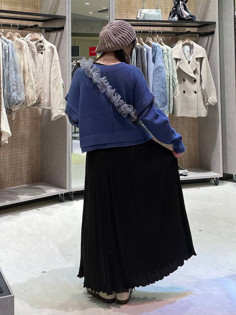 ベージュ系のワンピース、ブルー系のニット/セーター、グレー系のスマホグッズを着用したレディースの冬コーディネートの5枚目の写真