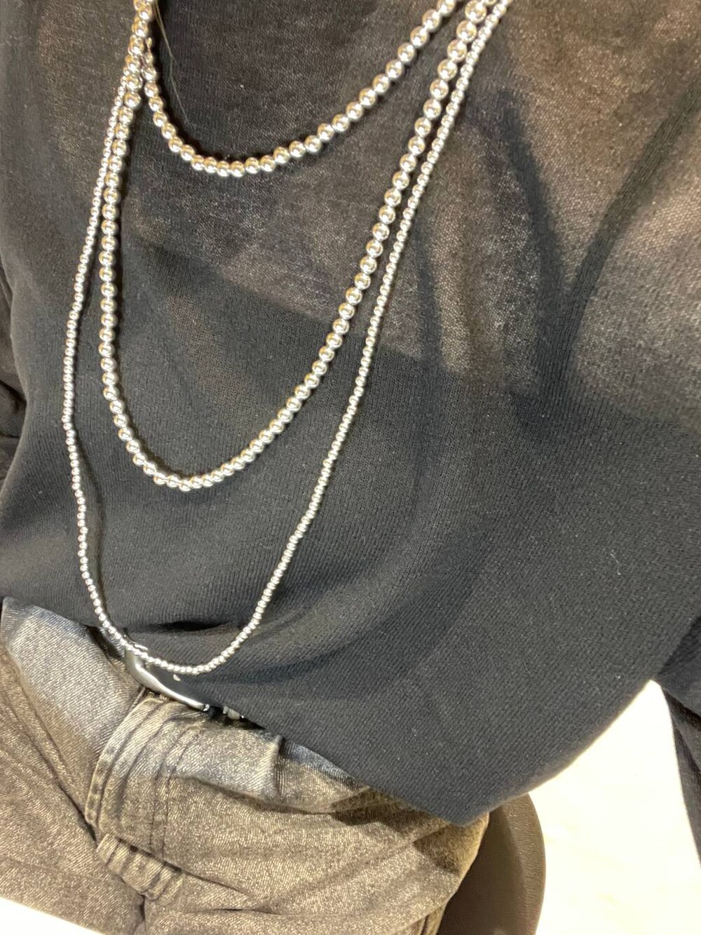 ブラック系のニット/セーター、グレー系のデニムパンツ、シルバー系のネックレスを着用したレディースの春コーディネートの2枚目の写真